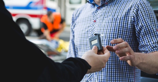 police officer giving the breathalyzer to the driver